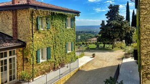 Ein Innenhof mit einem Efeu bewachsenen Gebäude, blauem Himmel und Blick auf die Landschaft.