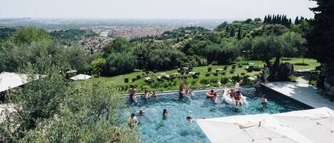 Piscina rodeada de vegetación exuberante y una vista de un paisaje urbano distante.