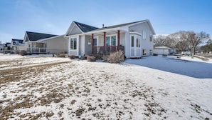 A single-story house with a covered porch and a snow-covered lawn.