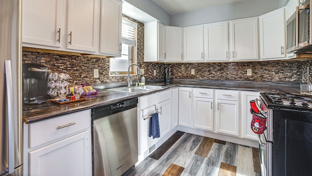 A modern kitchen with white cabinets, a granite countertop, and a stainless steel dishwasher.