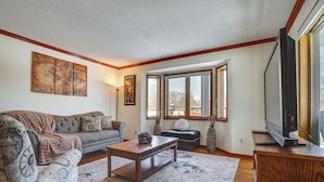 A living room with a sofa, coffee table, and a television on a wooden cabinet.