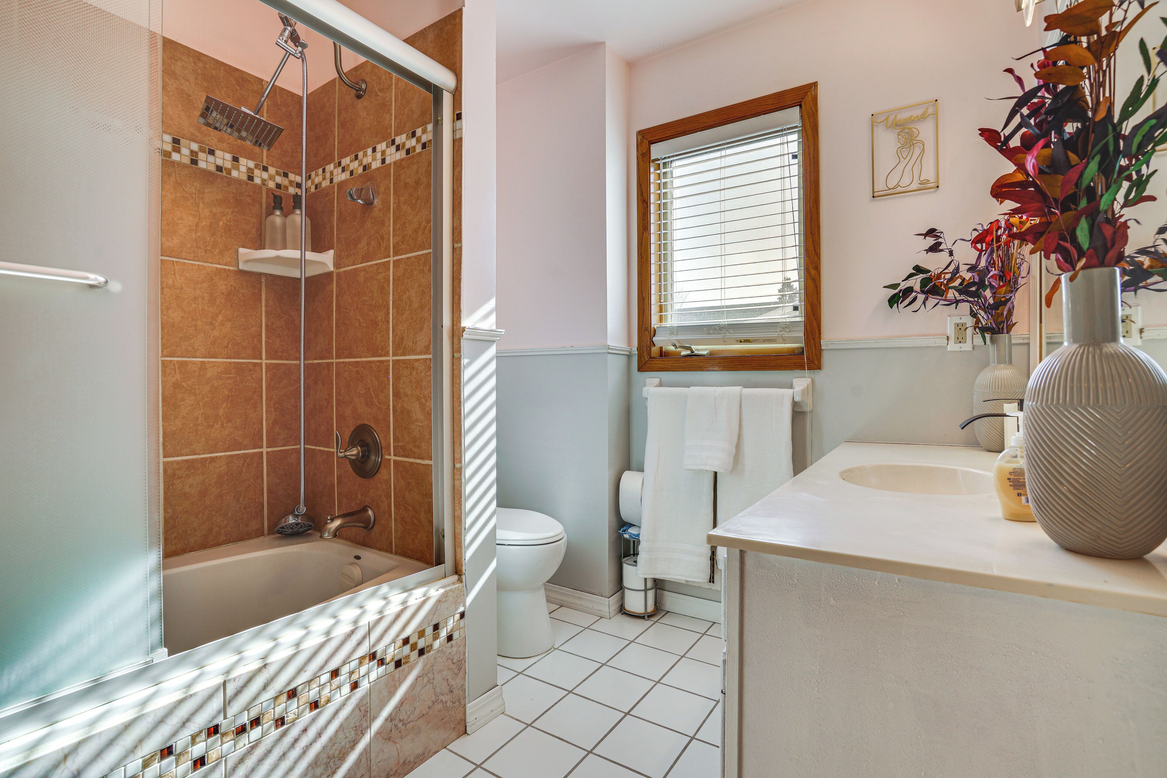 Ein Badezimmer mit Duschkabine, Badewanne, Toilette und Waschbecken mit dekorativen Vasen.