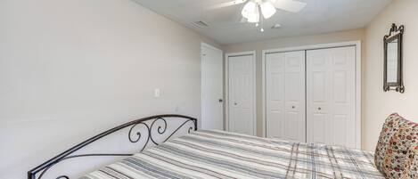 Un dormitorio con una cama, un ventilador de techo y dos puertas blancas.