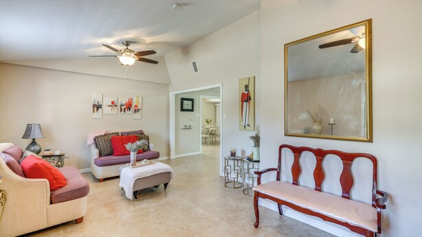 A spacious living room with a high ceiling, a ceiling fan, a large mirror, and a dining area in the background. - Cozy Jacksonville Home ~ 12 Mi to Downtown! (Jacksonville)