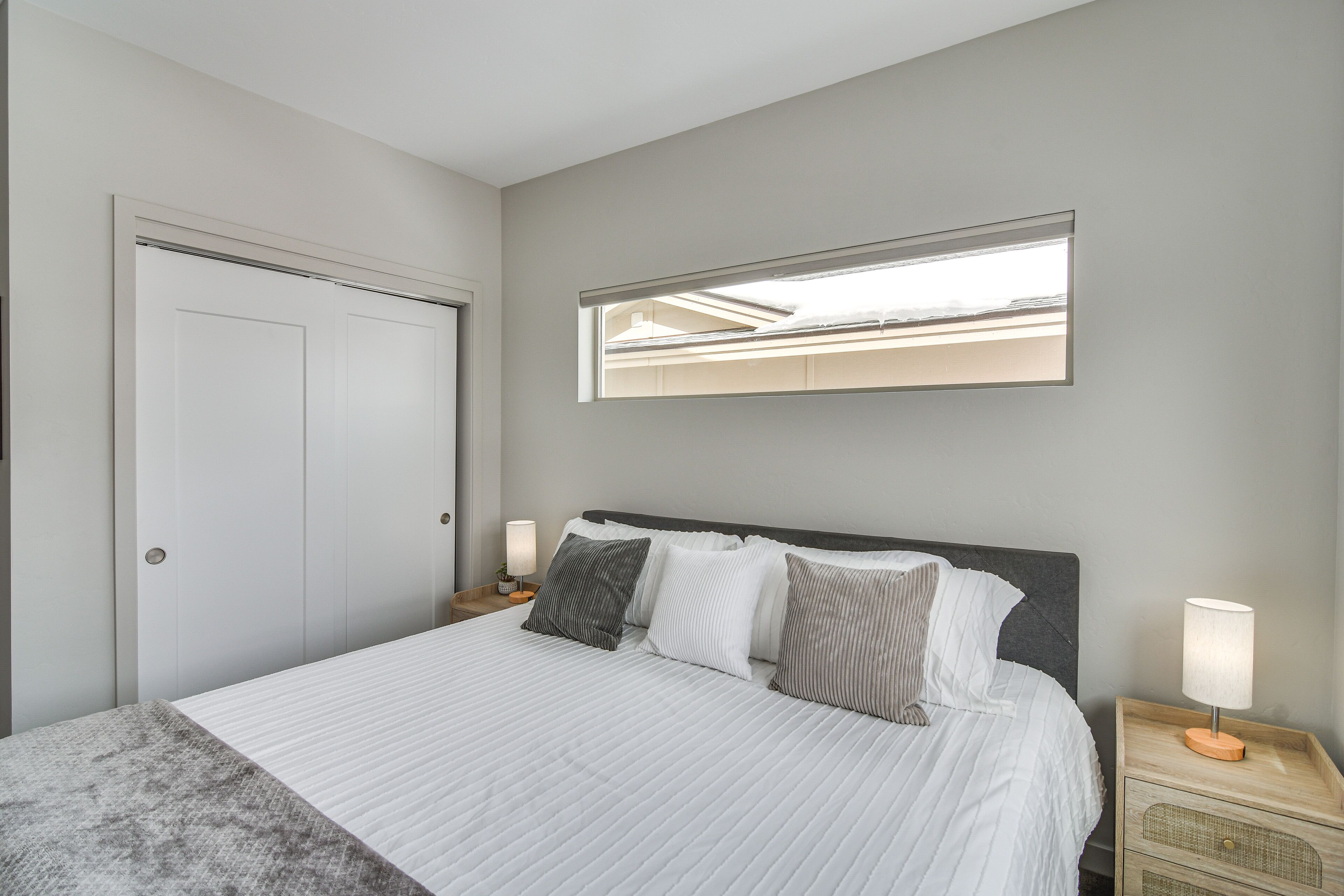 A bedroom with a bed, a nightstand, a mirror, and a wardrobe.