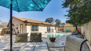 Un jardin avec une piscine, des chaises de patio et un espace salon abrité.