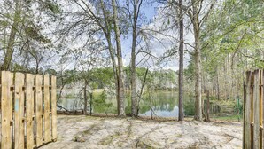 A concrete pathway leading to a wooden gate, surrounded by trees and a body of water. - Updated Tallahassee Townhome: 3 Mi to Downtown! (Tallahassee)