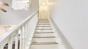 A staircase with white railings and wooden steps leading to a landing with a light fixture. - Updated Tallahassee Townhome: 3 Mi to Downtown! (Tallahassee)
