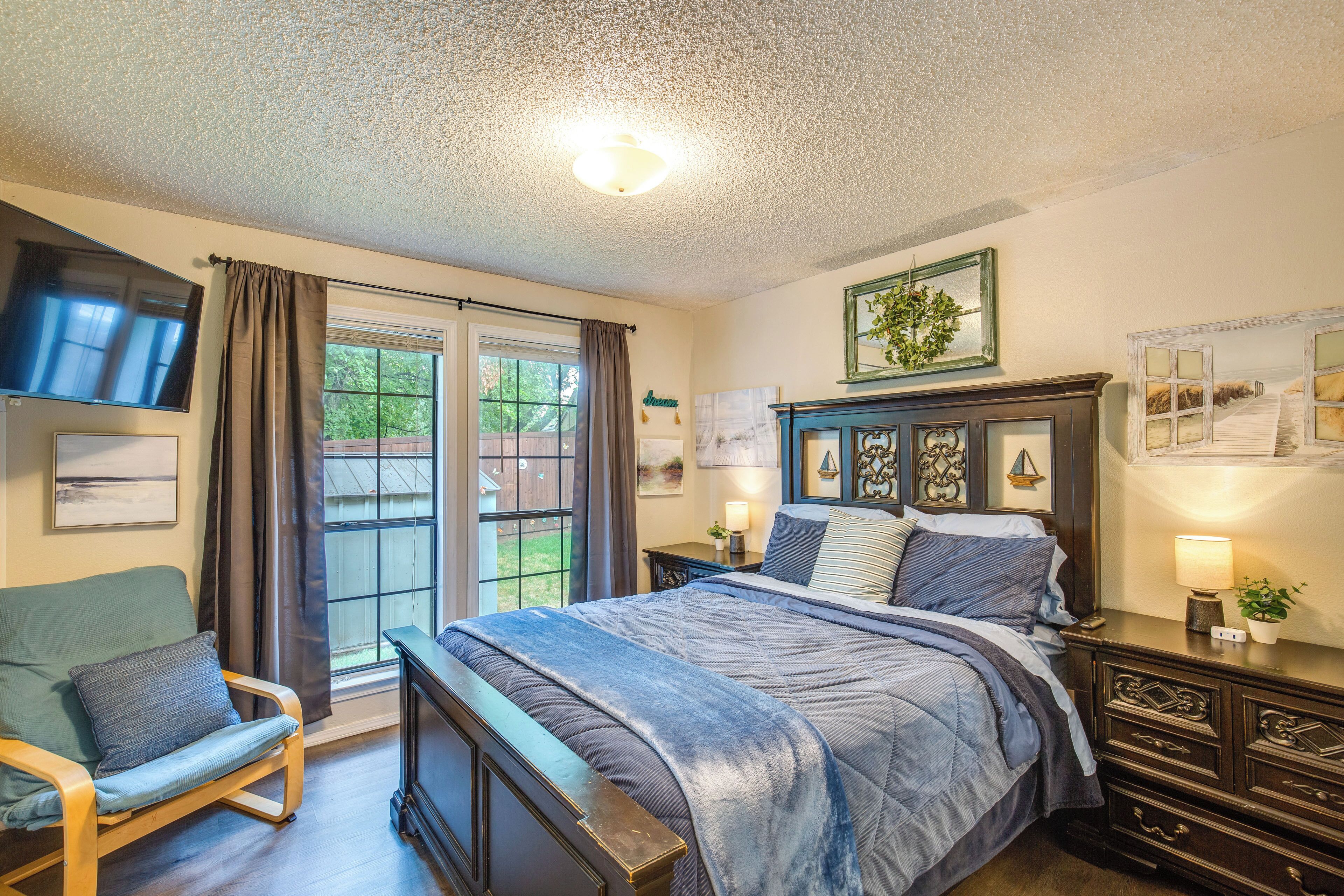 A bedroom with a bed, a chair, a nightstand, and a window.
