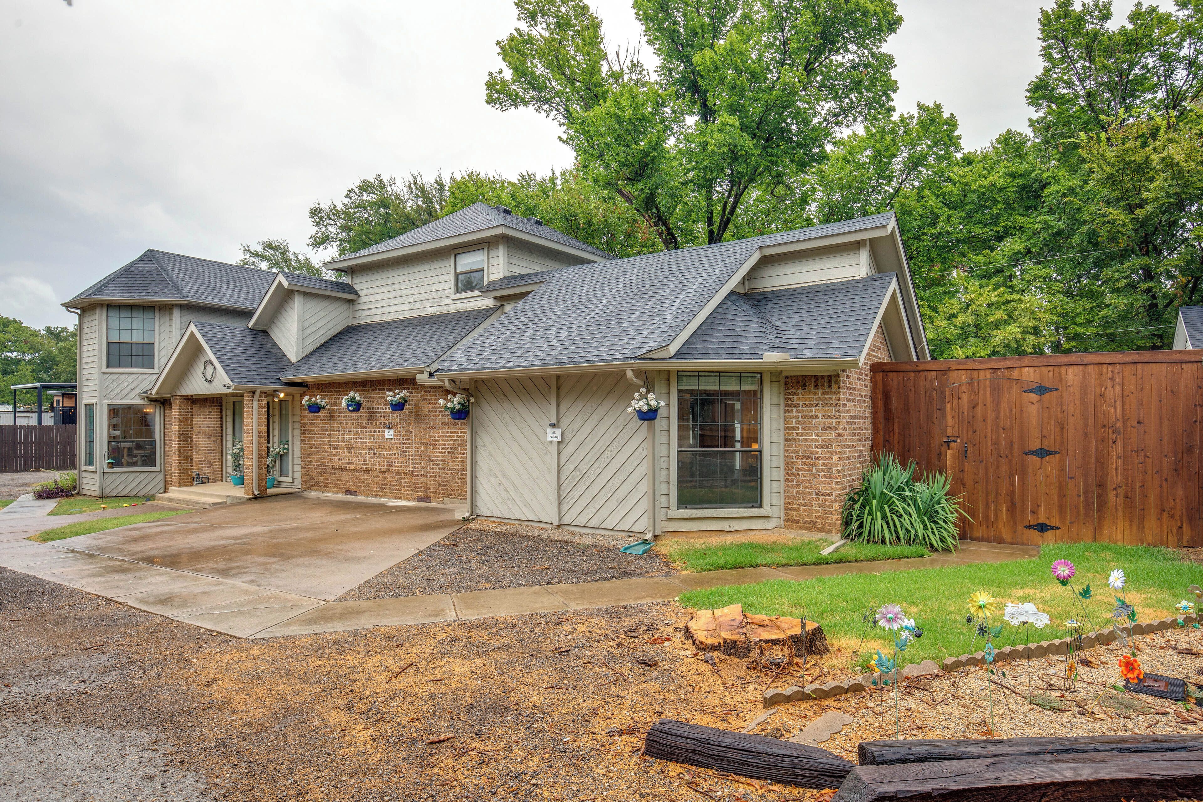 A two-story house with a covered patio, a fenced yard, and a landscaped garden with flowers.