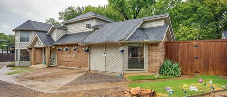 A two-story house with a covered patio, a fenced yard, and a landscaped garden with flowers.