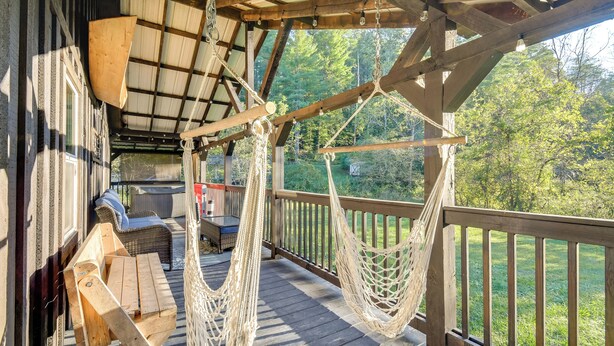 Una terraza de madera con una hamaca, mobiliario exterior y vistas del bosque circundante.