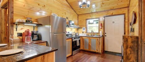 Cocina de cabaña de madera con refrigerador, horno, microondas y alacenas de madera.