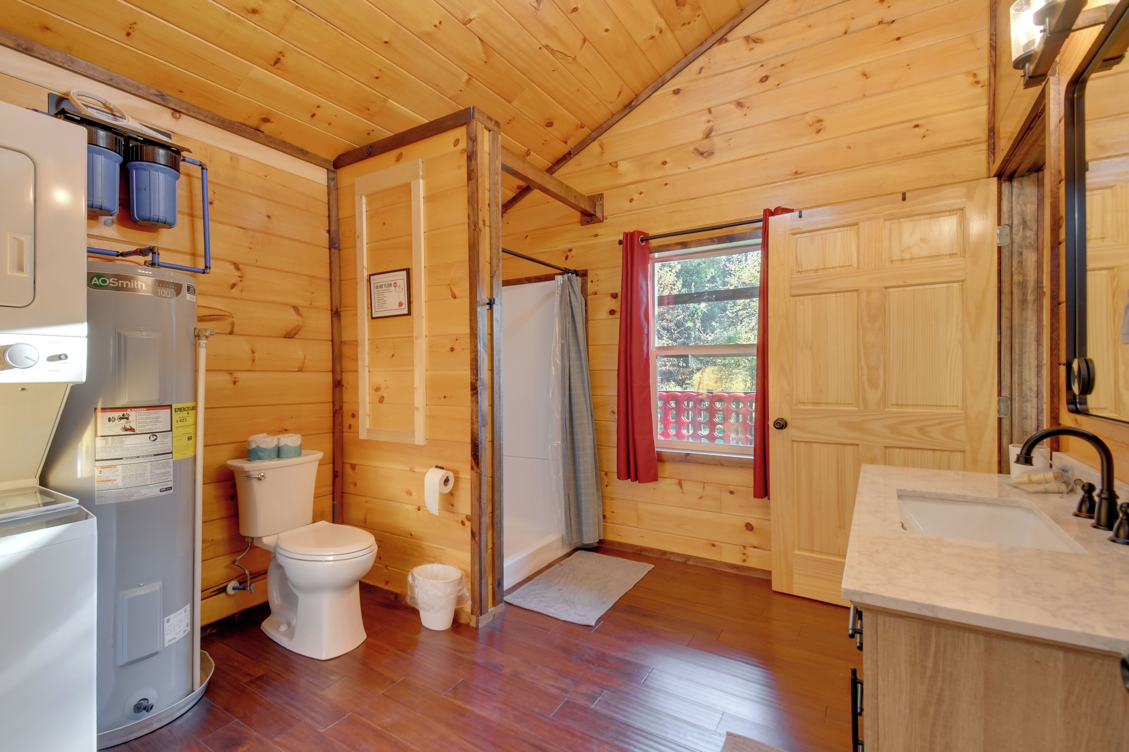 A wooden cabin bathroom with a toilet, sink, and shower.
