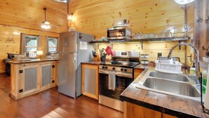 Cocina de cabaña de madera con refrigerador, estufa, microondas y pileta.