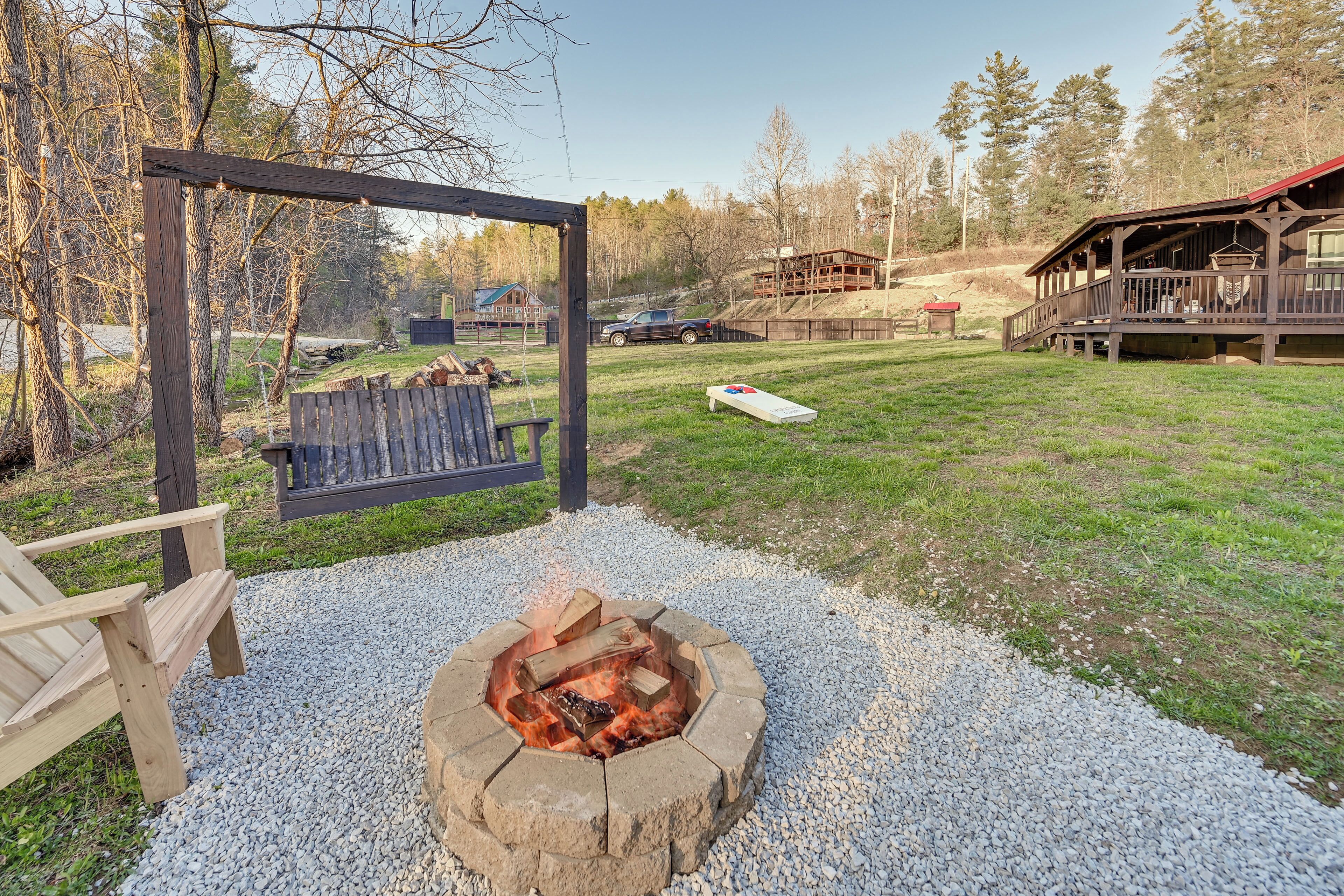 A wooden deck with a fire pit, a swing, and a bench.