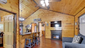Interior acogedor de una cabaña de madera con comedor, chimenea y sala de estar con sofá.