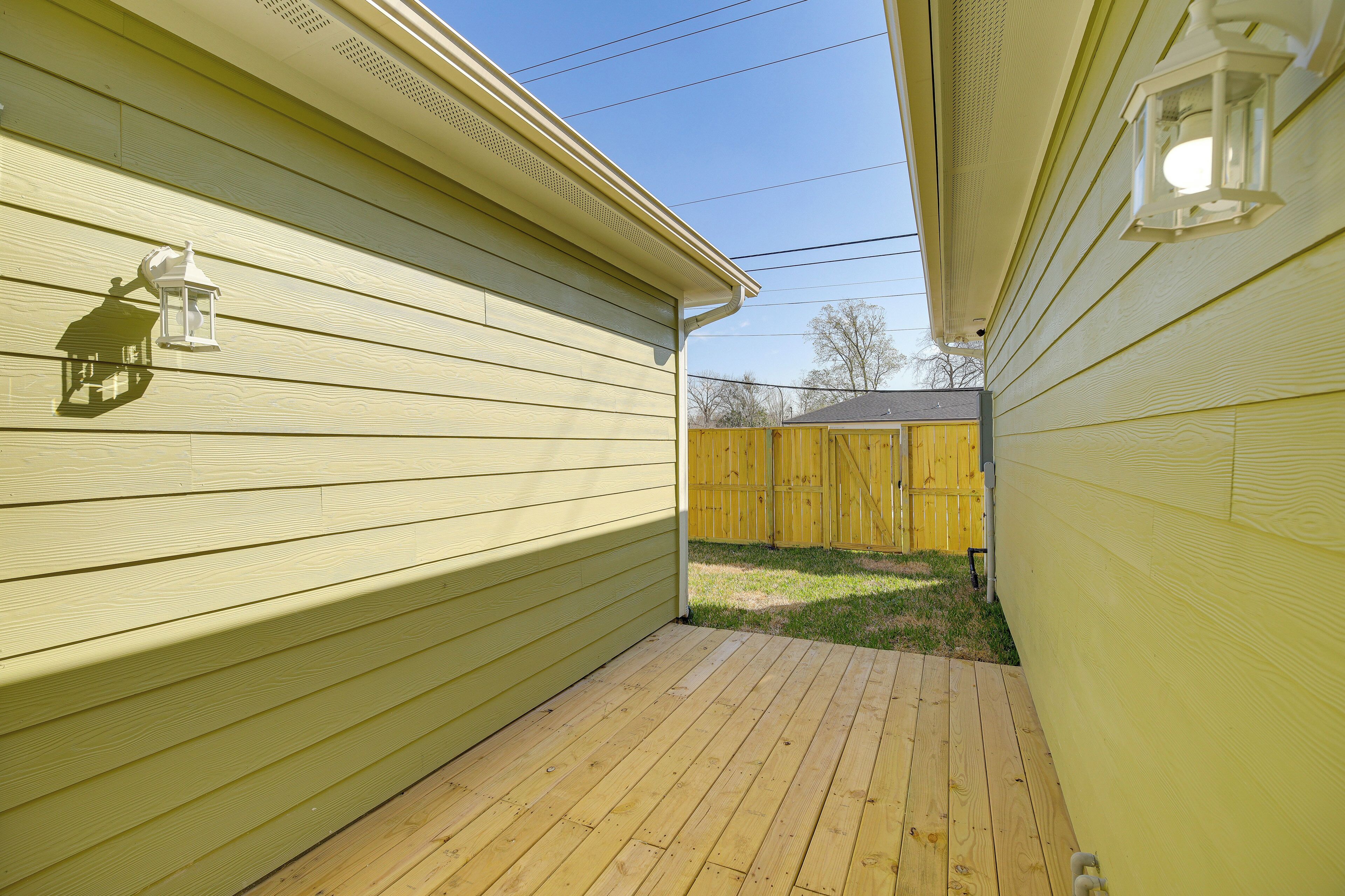 A wooden deck with a yellow fence and a house with siding.