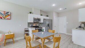 A modern kitchen with white cabinetry, a dining table with chairs, and a small side table. - Easy Interstate Access: Quiet Houston Home! (Houston)