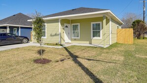 A single-story house with a front porch, a small tree, and a wooden fence. - Easy Interstate Access: Quiet Houston Home! (Houston)