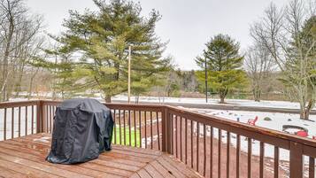 Enjoy al fresco dining on the deck overlooking the serene landscape with a body of water and surrounding trees.
