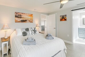 A bedroom with a bed, two bedside tables with lamps, a ceiling fan, and artwork on the walls. - Englewood Vacation Rental ~ 2 Mi to Beach! (Englewood)