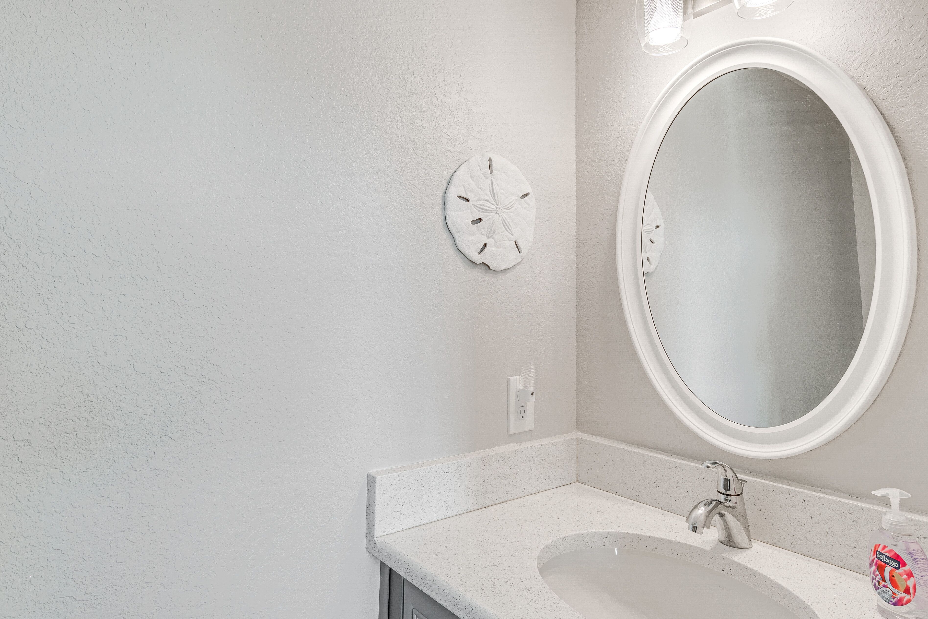 A bathroom with a white sink, a round mirror, and a wall clock.