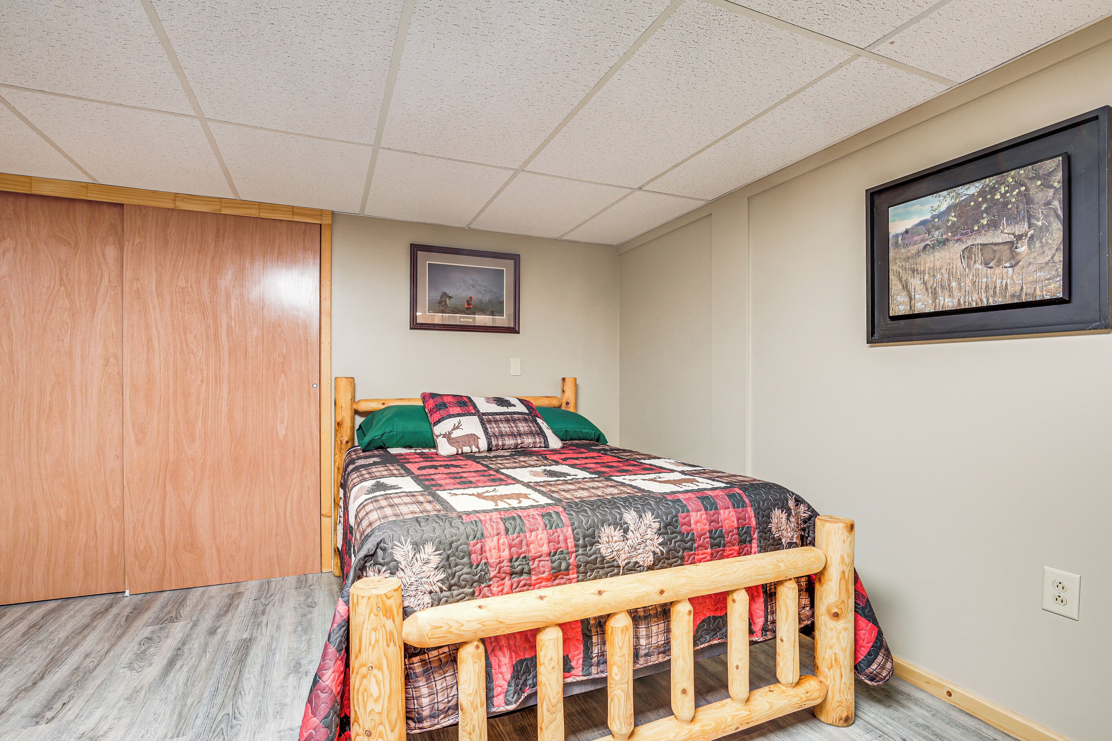 Un dormitorio con estructura de cama de madera, colcha y dos cuadros en la pared.