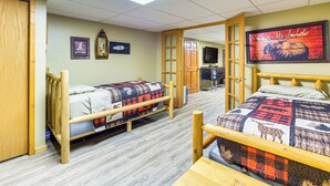A room with two wooden bunk beds, a television, and a framed picture on the wall. - Hayward Home w/ Private Deck, Fire Pit & Kayak! (Hayward)