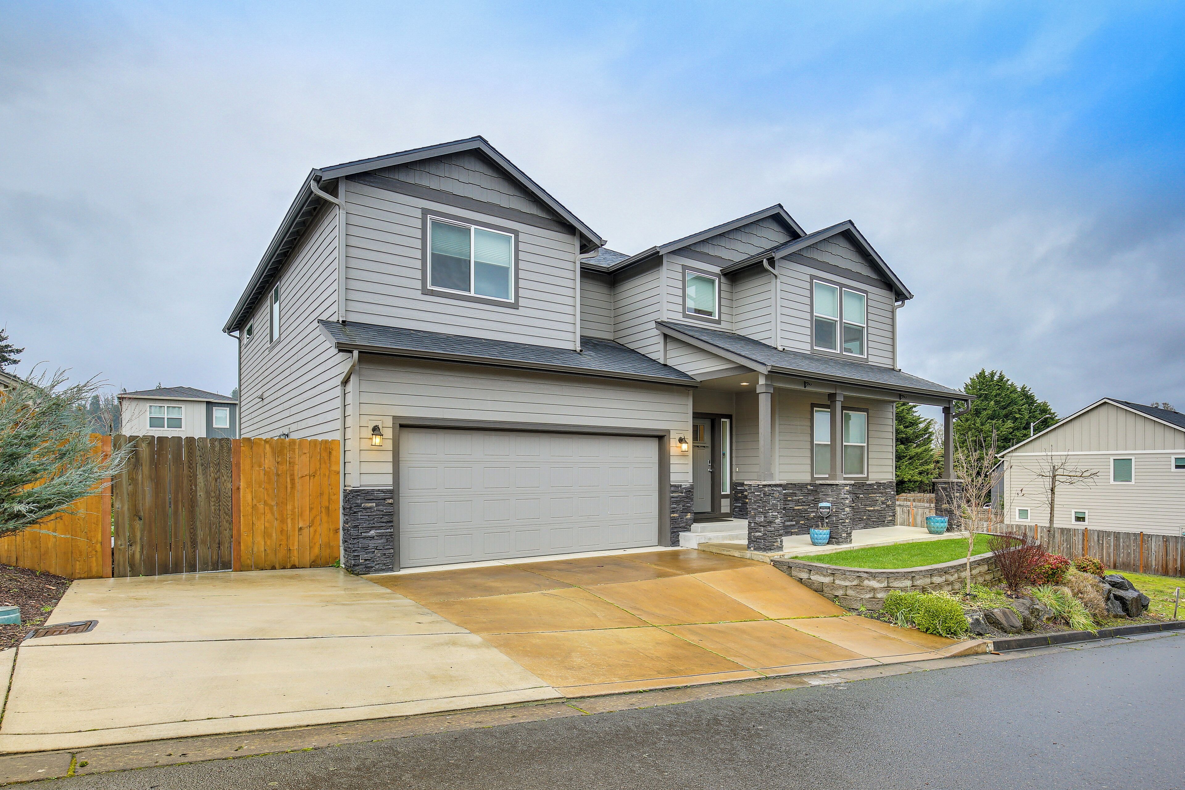 A two-story house with a garage, a stone accent wall, and a wooden fence.