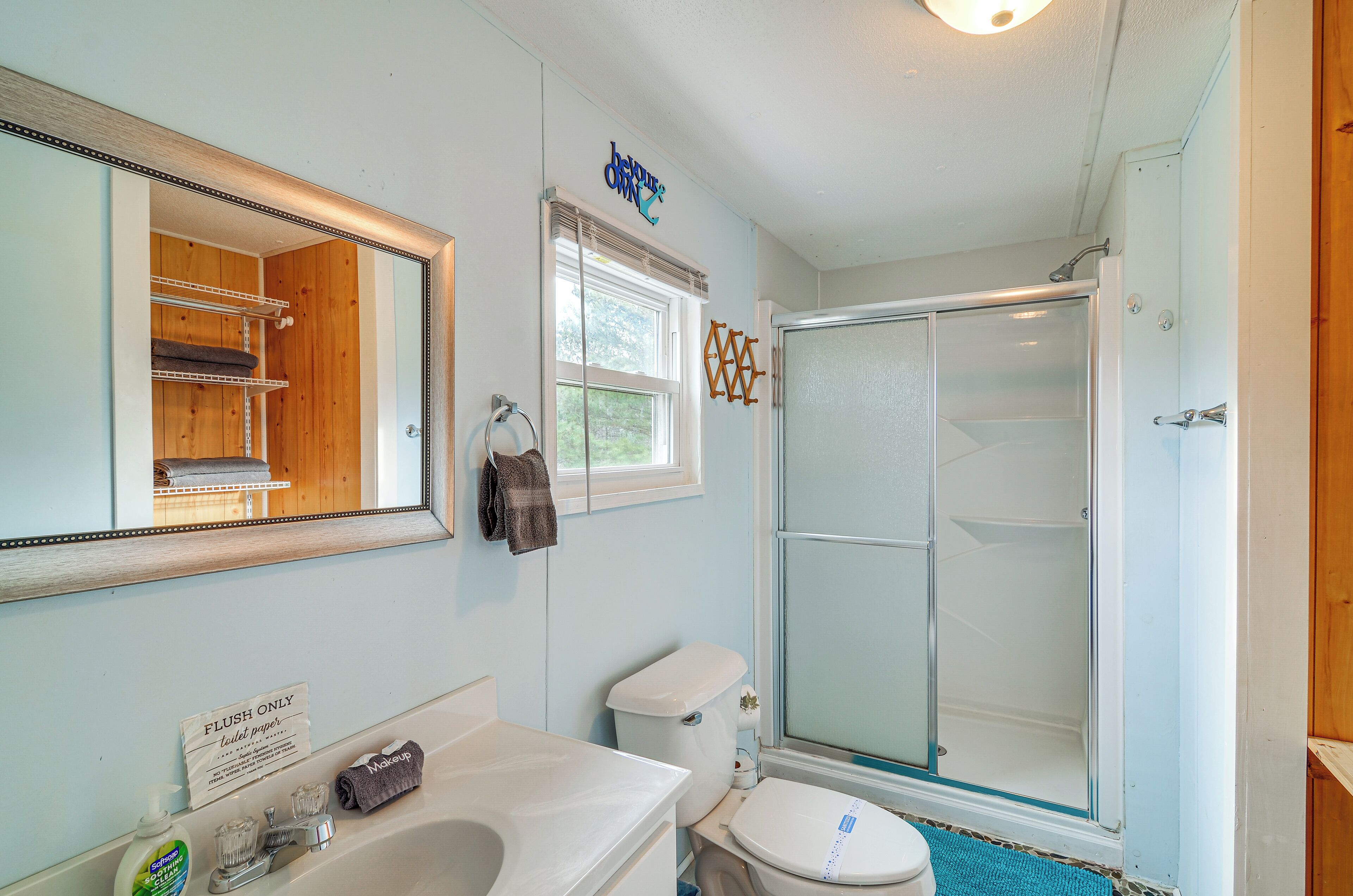 A bathroom with a toilet, sink, and shower. There is a sign on the wall that says "FLUSH ONLY".