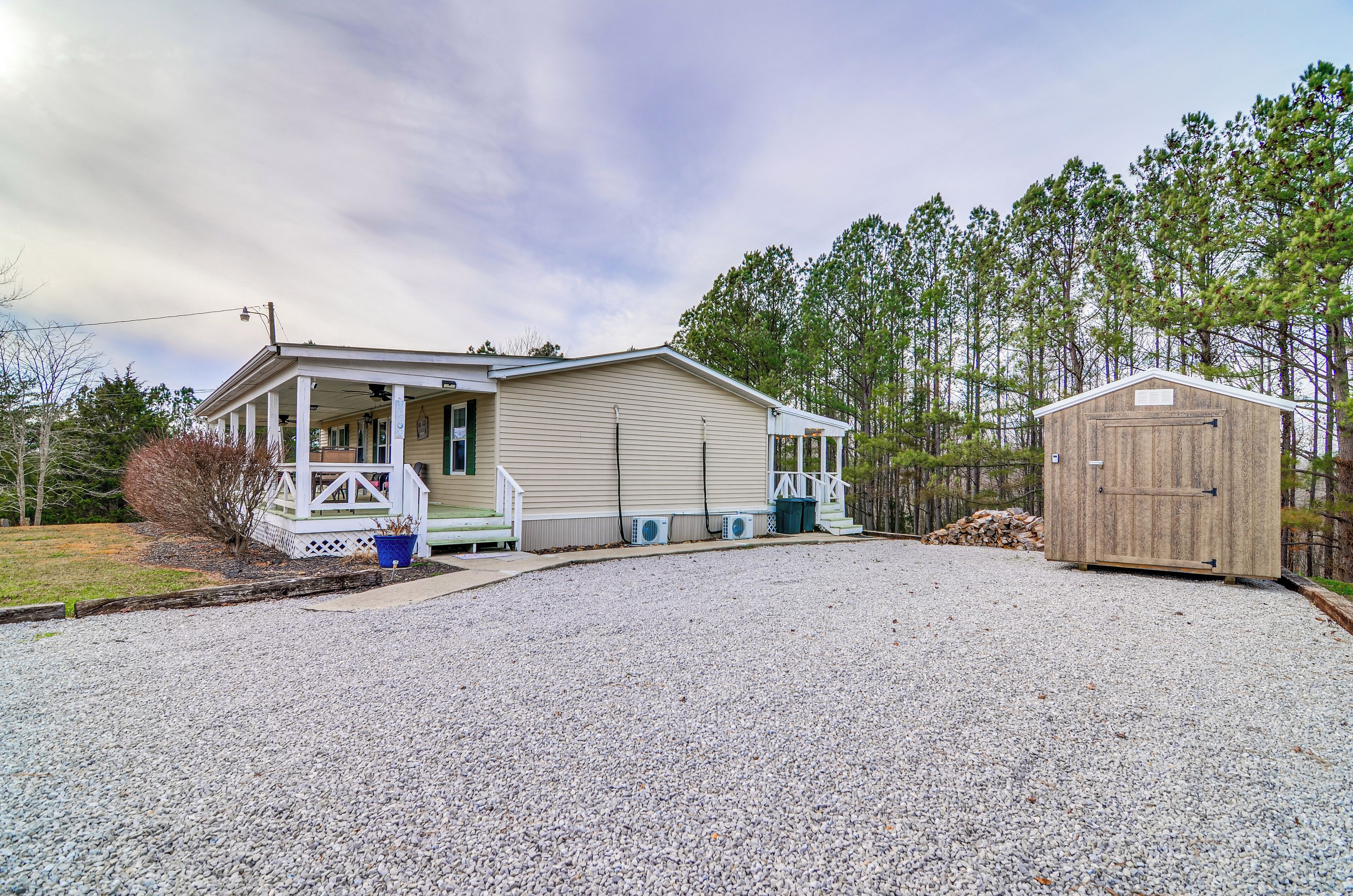 A single-story house with a porch, a covered garage, and a gravel driveway.