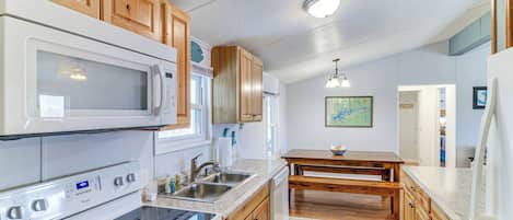 A kitchen with wooden cabinets, a microwave, stove, and a sink.