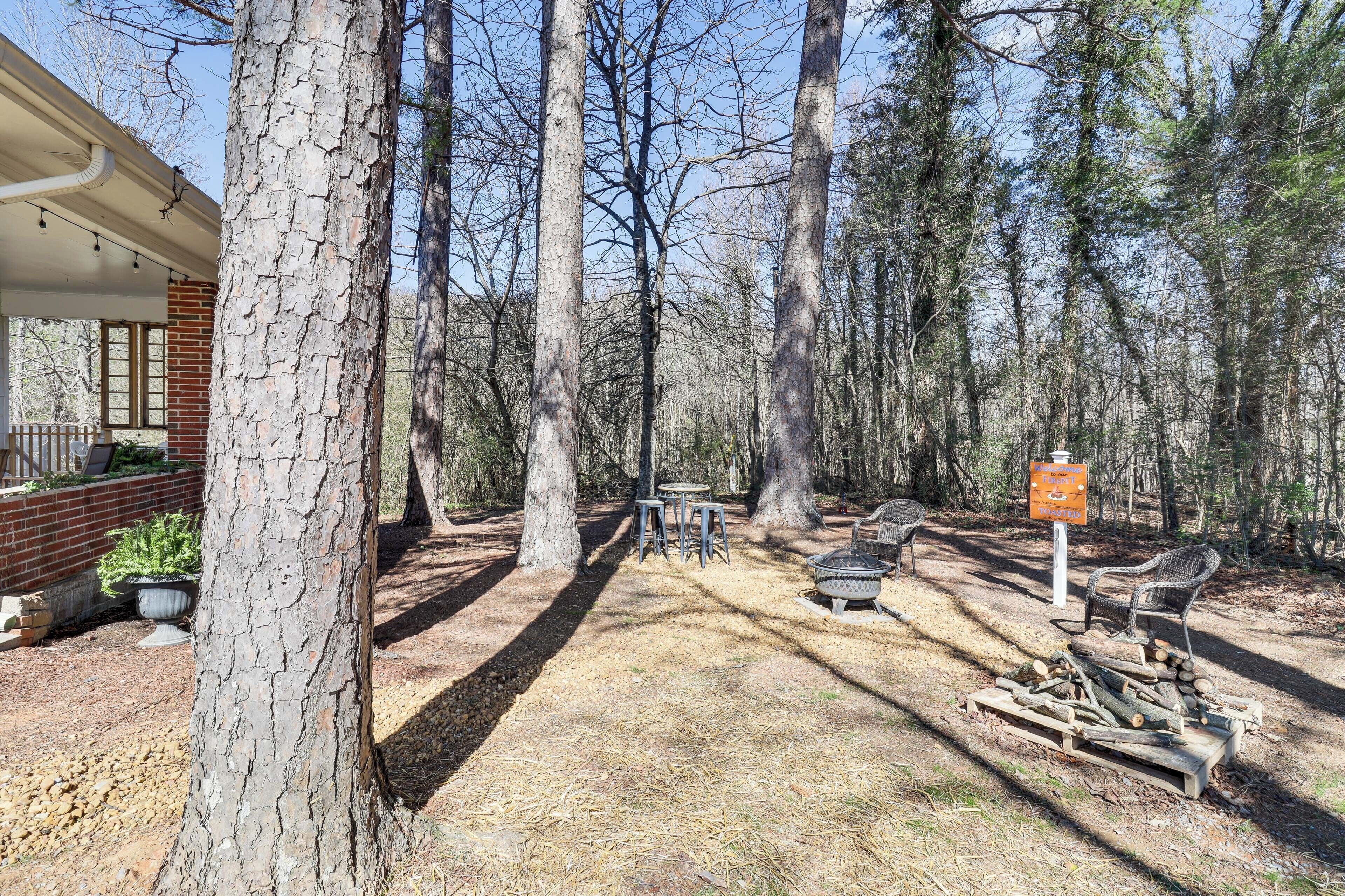 A rustic outdoor area with a covered seating area, a fire pit, and a picnic table.