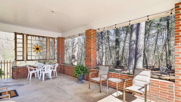 A covered patio area with brick walls, a wooden table, white plastic chairs, and a potted plant. - Peaceful Trenton Home w/ Patio Near Hiking! (Trenton)