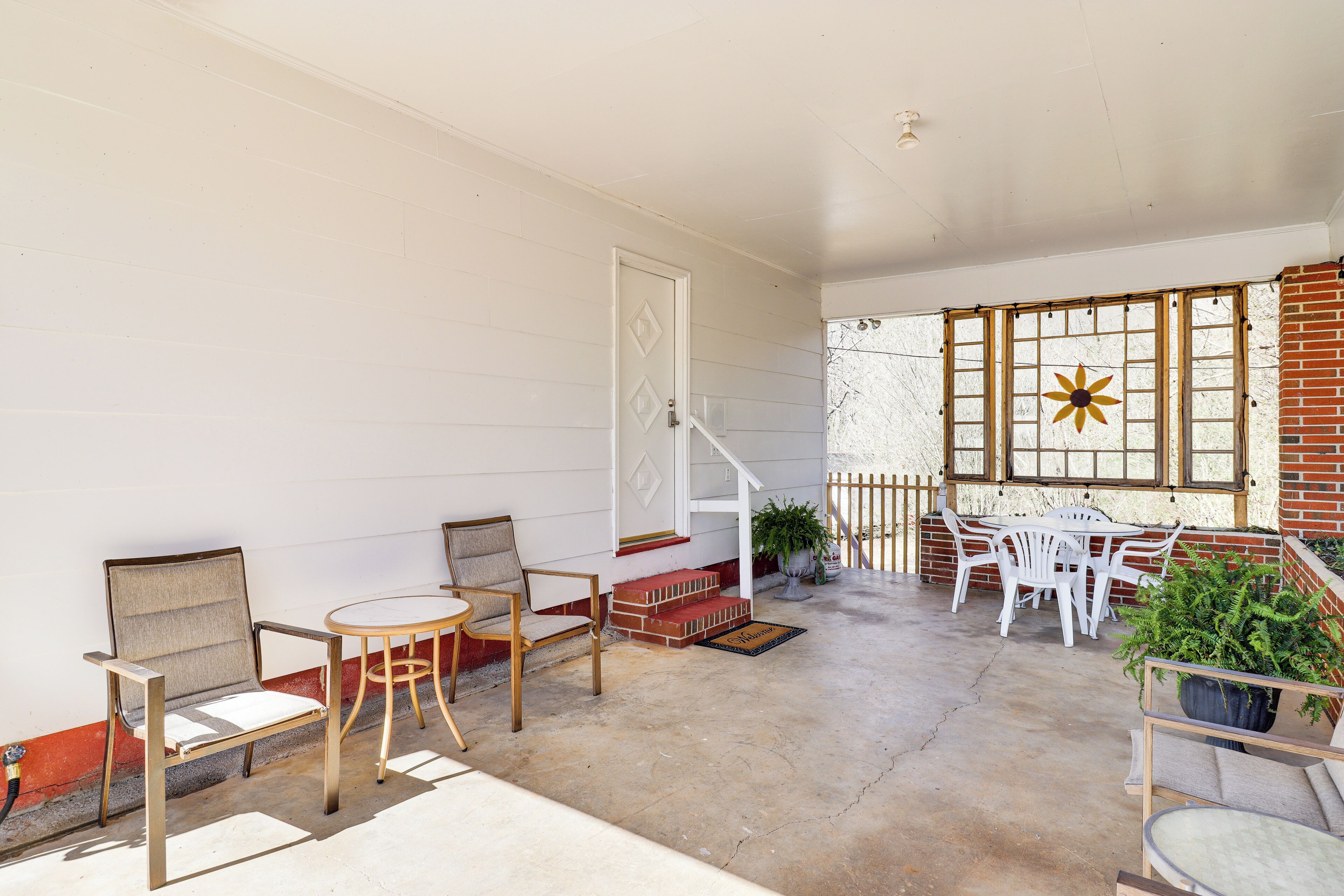A covered patio with outdoor seating, a staircase, and a brick wall.
