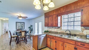 A kitchen with wooden cabinets, a dishwasher, and a large window with blinds. - Peaceful Trenton Home w/ Patio Near Hiking! (Trenton)