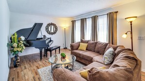 A living room with a grand piano, a brown sofa, a glass coffee table, and a vase with flowers. - Peaceful Trenton Home w/ Patio Near Hiking! (Trenton)