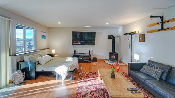 A modern living room with a bed, sofa, TV, fireplace, and a large window. - Quaint Mount Vernon Studio Rental w/ Big Lake View (Mount Vernon)