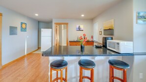 A modern kitchen with a central island, wooden bar stools, and a refrigerator. - Quaint Mount Vernon Studio Rental w/ Big Lake View (Mount Vernon)