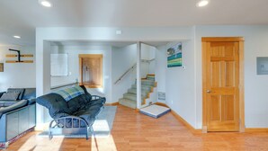 A modern living room with a sofa, a wooden floor, a staircase, and a wooden door. - Quaint Mount Vernon Studio Rental w/ Big Lake View (Mount Vernon)