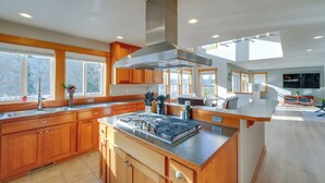 A modern kitchen with wooden cabinets, a stainless steel range hood, and a large island with a built-in stove. - Stunning Mount Vernon Home w/ Big Lake Views! (Mount Vernon)