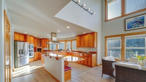 A spacious kitchen with wooden cabinets, a central island, and a dining area with wicker furniture. - Stunning Mount Vernon Home w/ Big Lake Views! (Mount Vernon)