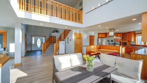 A spacious living area with a high ceiling, wooden staircase, and a kitchen area with wooden cabinets and a stainless steel range hood. - Stunning Mount Vernon Home w/ Big Lake Views! (Mount Vernon)