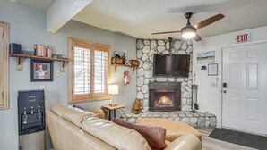 A cozy living room with a stone fireplace, a mounted TV, and a water dispenser. - Cozy Cabin w/ Deck - 2 Mi to Bear Mountain Resort! (Big Bear Lake)