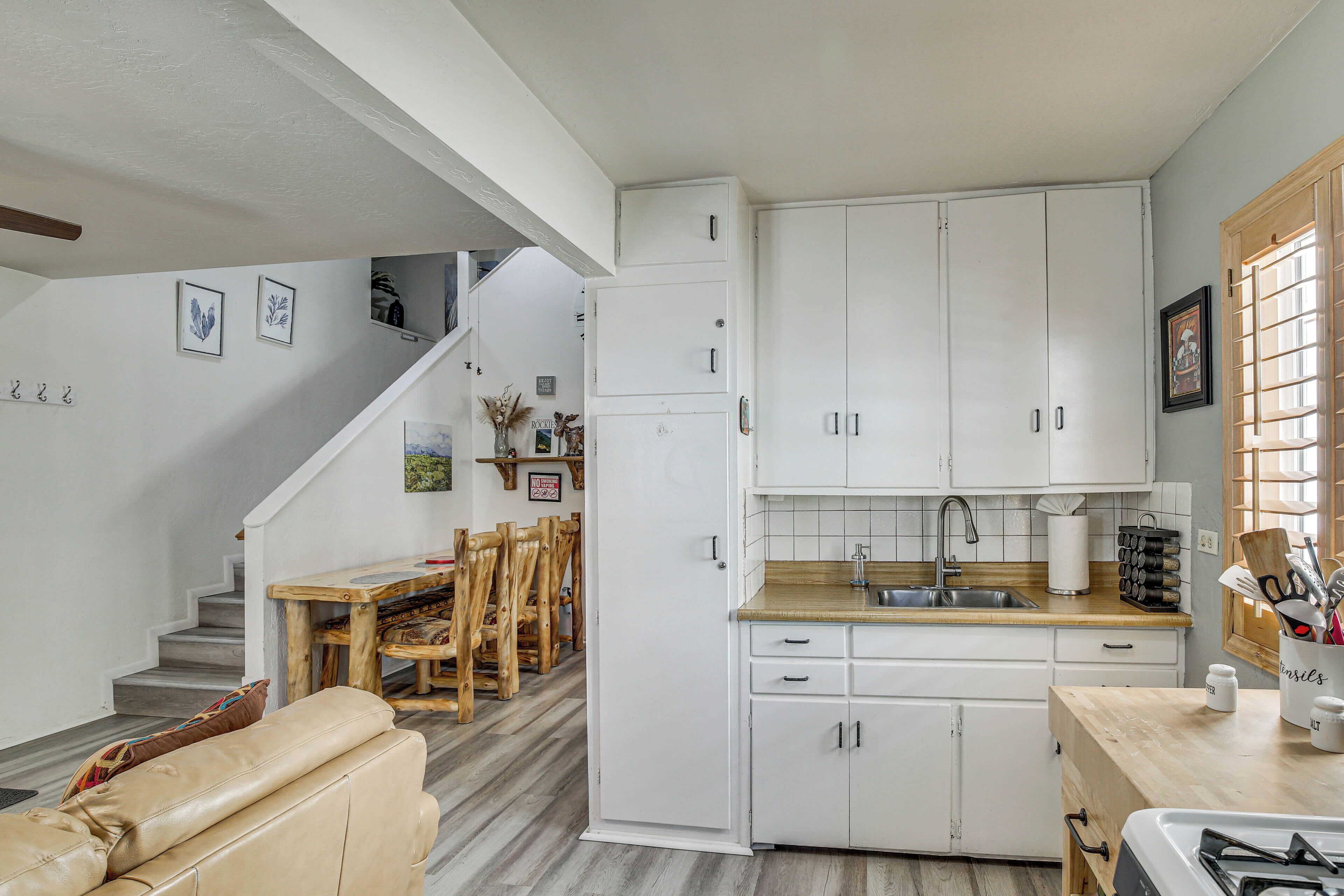 Una cocina moderna con armarios blancos, encimera de madera y una zona de comedor con mesa y sillas.
