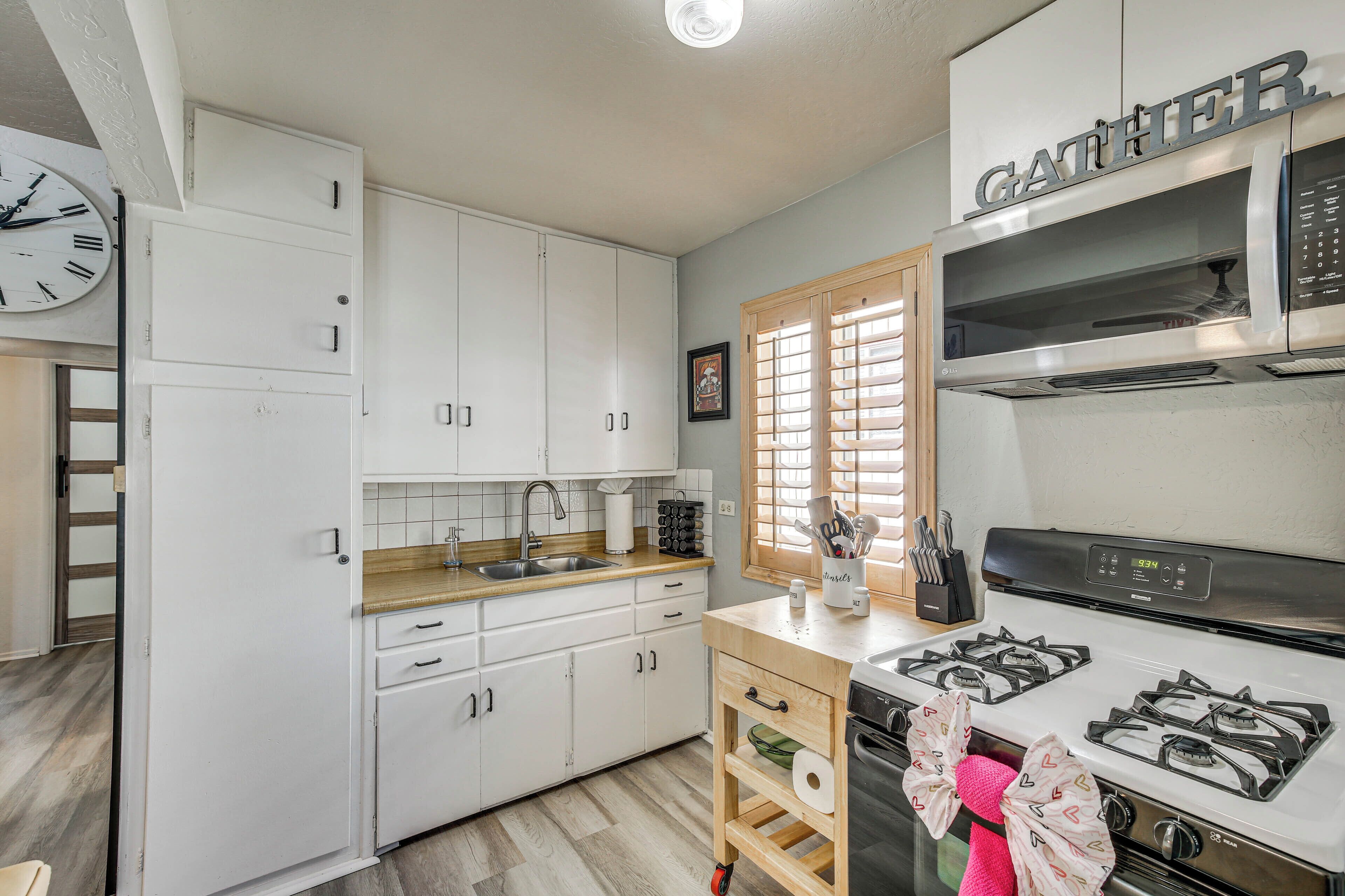 A kitchen with white cabinets, a stainless steel stove, and a wooden countertop.
