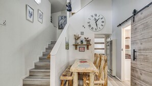 A staircase leading to a dining area with a wooden table and chairs, a clock on the wall, and a sliding barn-style door. - Cozy Cabin w/ Deck - 2 Mi to Bear Mountain Resort! (Big Bear Lake)