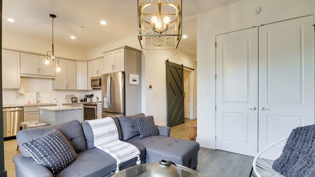 A modern living room with a grey sofa, a glass coffee table, and a white chair. - Downtown Lynchburg Condo w/ James River Views (Lynchburg)