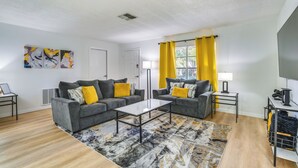 A modern living room with two grey sofas, a glass coffee table, and a patterned rug. - Home w/ Screened Porch, Near Weeki Wachee Springs! (Spring Hill)